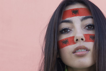 Flag of Albania painted on a face of a smiling albanian young woman. Copyspace.