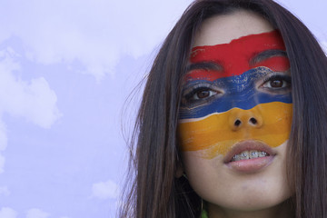 Flag of Armenia painted on a face of a smiling armenian young woman. Copyspace.