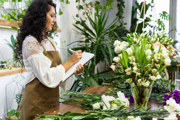 Obraz premium Attractive young woman florist is working in a flower shop.