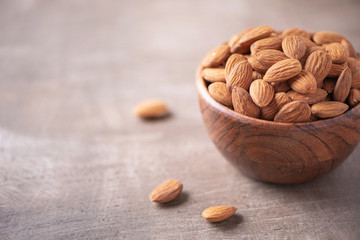 Almond nuts in wooden bowl on wood textured background. Copy space. Superfood, vegan, vegetarian food concept. Macro of almond nut texture, selective focus. Healthy snack