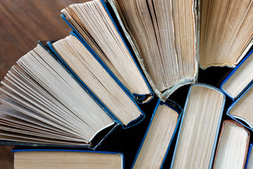 Naklejka premium Old and well used hardback books or text books in a book shop or library. Many Books Piles. Hardback books on wooden table top view. Back to school background with copy space.
