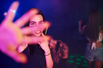Defocused hand. Young people is having fun in night club with colorful laser lights
