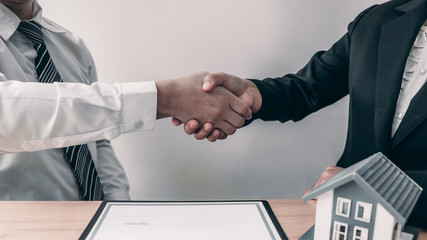 Agent and customer are shaking hand after finishing an advice for taking the house insurance