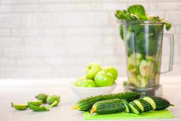 Green set of products for a healthy smoothie with copy space. A woman begins to cut a cucumber to make a smoothie. Morning detox for a healthy lifestyle, weight loss, ketone diet, raw food diet