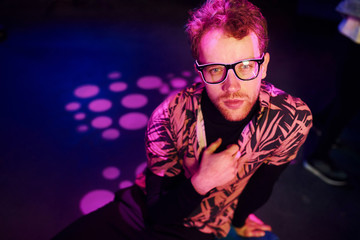 Young man in glasses have fun inside of night club with pink lightings