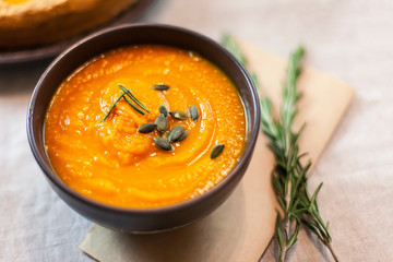 Pumpkin soup decorated on a table with a sprig of rosemary