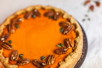 Pumpkin homemade pie on a gray linen background with top view of food ingredients for decoration