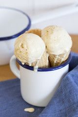 bolas de helado derritiéndose en cucurucho sobre taza y paño azul