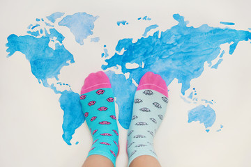 Legs in bright funny different socks on map of world. Down syndrome concept. 