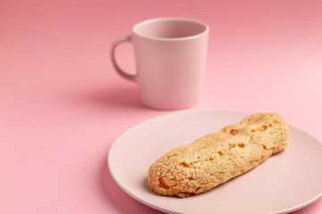 Eclair on the plate. Pink pastel background. Dessert concept, minimalism