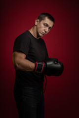 Fototapeta na wymiar Male athlete boxer with gloves in his hands posing against a dark red background