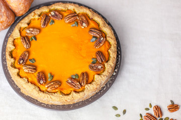 Pumpkin homemade pie on a gray linen background with top view of food ingredients for decoration