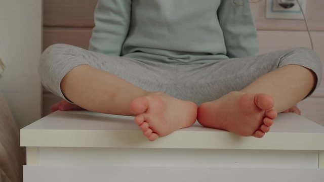 Child legs while baby girl sitting. Playing game.