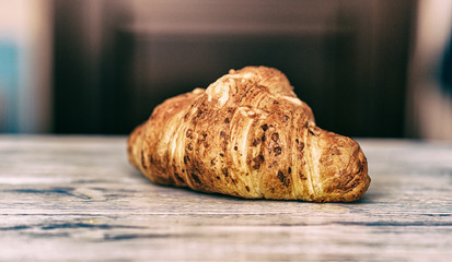 Croissant on a light wooden background. Photographed in high key.