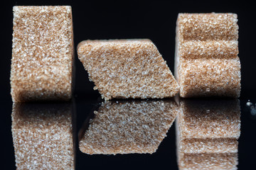 A piece of refined sugar with cinnamon on a black background. Photographed close-up.
