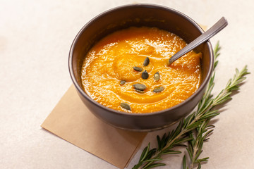 Pumpkin soup decorated on a table with a sprig of rosemary
