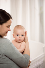 Young mother hugging her newborn child. Love, trust and tenderness concept. Bedding and textile for nursery.