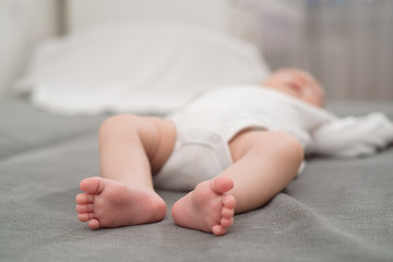 Baby sleeps in bed, view of small baby legs