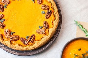 Pumpkin pie decorated with pecans on a served table for an autumn party food