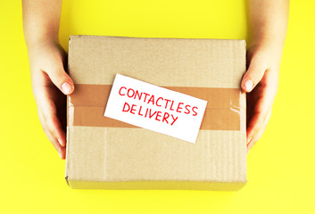 contactless delivery. parcel in hand on a yellow background