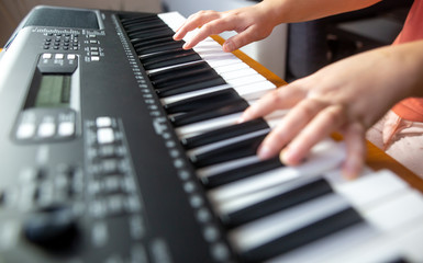 Fototapeta premium Young female beginner teaches itself playing on the electric piano, instrument playing, teachning