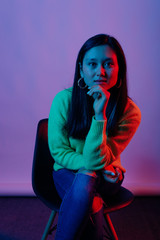 Portrait of young asian woman sitting on chair and looking confident at camera