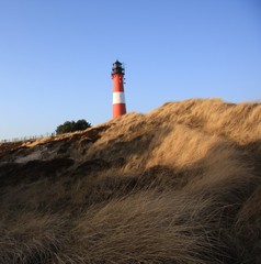 Red and white lighthouse on the island, blue sky background
