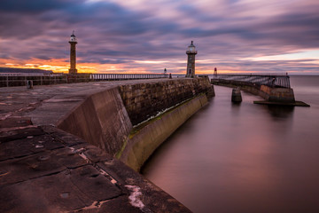 Long exposure of Whitby pier and lighthouses at sunset