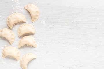 Cooking dumplings on a light background. Dumplings with potatoes on a wooden table. Top view