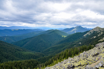  Beautiful mountain landscape. amazing forest and huge stones on top of the hillside near the peak of mountain range at cloudy day. Carpathians, Ukraine