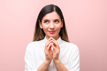 young sneaky woman, scheming something for april first, fools day against pink background