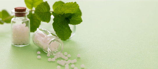 Homeopathy, globules scattered out of glass bottle, green background