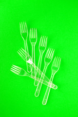 White disposable forks on green background close-up - Environmental problem concept