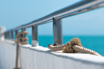 Ship railing with rope and blue sea