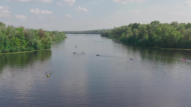 sunny summer day over green islands on a river in a northern city, people actively spend time on the river, kayaking and wake boarding, wake surfing after fast boats - Aerial Fligh