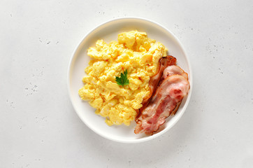 Scrambled eggs and fried bacon on plate