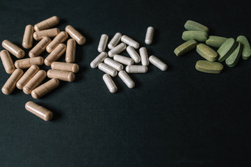 Different color vitamins and drugs against Coronavirus COVID-19. Dark background. Lay flat. Smooth image with shallow depth of field.
