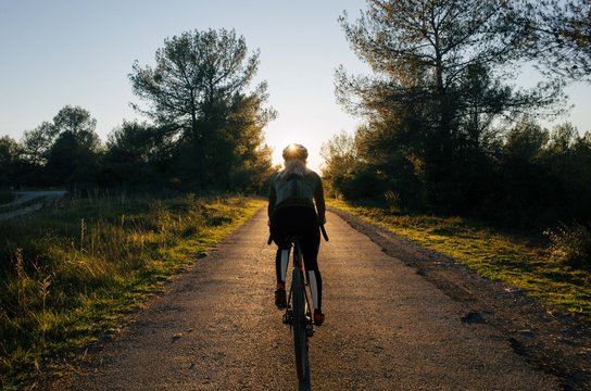 Young female cyclist rides into the sunset
