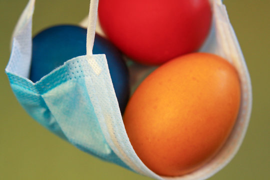 Vivid colored eggs in medical mask Easter 2020