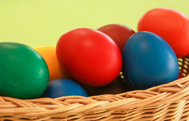Fototapeta na wymiar Easter eggs colors in basket green background