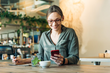 Caucasian businesswoman working at her desk in cafe. Female executive looking away and smiling. Woman working on laptop sitting at cafe.