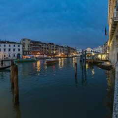 VENICE, ITALY - August 02, 2019: View from Rialto Bridge in Venice at sunset time. Venetian Grand Canal with historical buildings, hotels, tourist boats, piles, berths. Fish eye lens shot