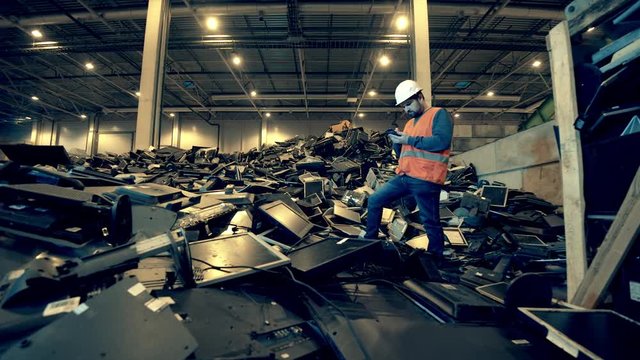 Male employee is standing on a pile of garbage in a dumpsite unit. Garbage, plastic recycling factory.