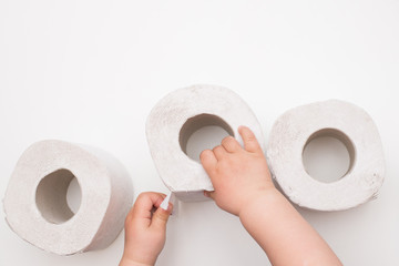 the child's hand takes out of the pile of toilet paper on white background. copy space