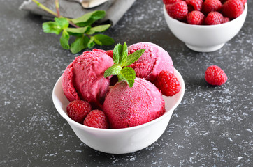 Raspberry ice cream scoop with fresh raspberries in bowl