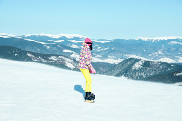 Female snowboarder on snowy slope in mountains. Winter vacation