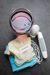 glass of red wine, face mask , gloves and othe medical objects on dark background