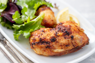 grilled chicken with lemon and salad on white dish