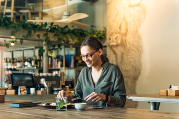 Fototapeta premium Young caucasian businesswoman eating tasty belgian waffles while sitting at cafe.