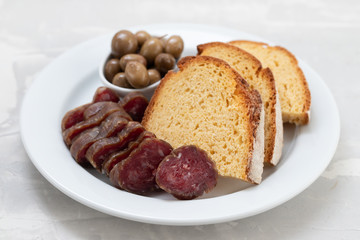 corn bread with smoked sausage and olives on white plate
